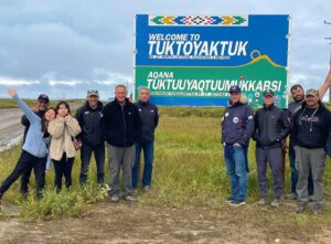 Guests posing with the Welcome to Tuktoyuktuk on their Mackenzie Arctic Expedition to the Arctic Ocean with North Star Adventures