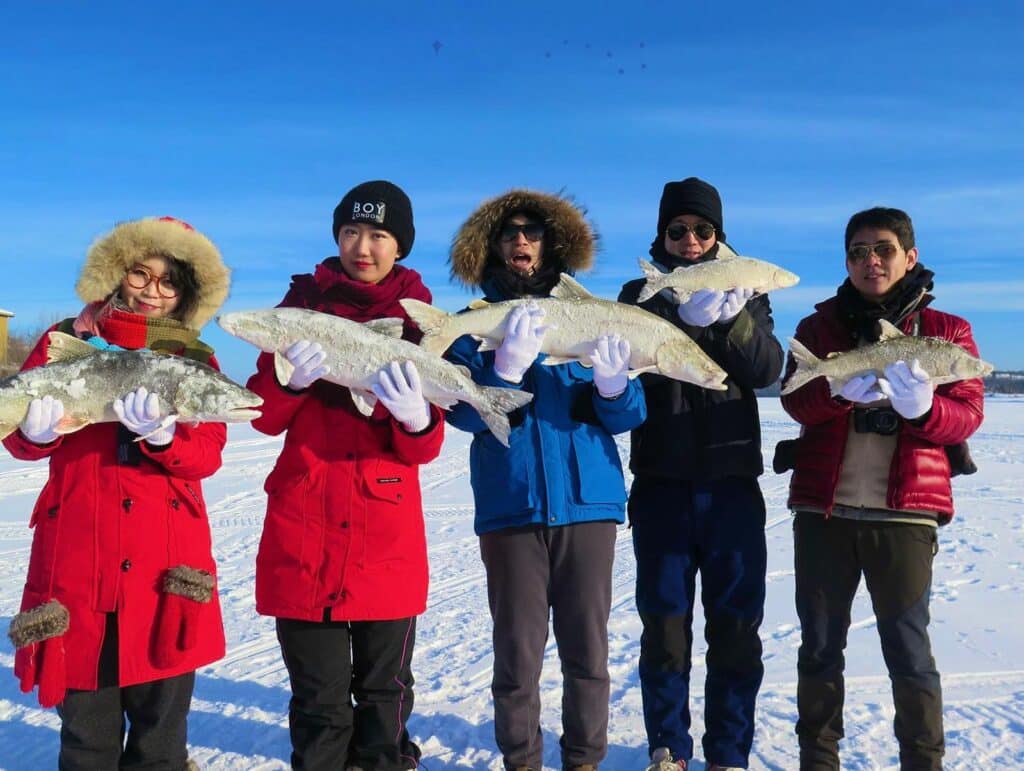 5 people hold fish that were caught ice fishing