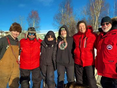 Group of people standing together with dogsled hosts