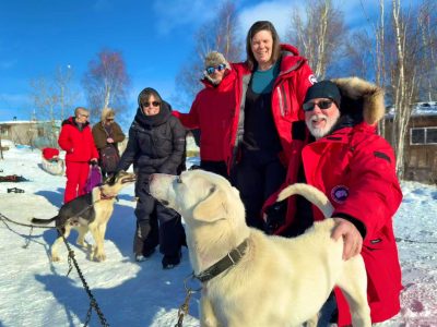 Group of people petting the dogs who will be pulling dogsled